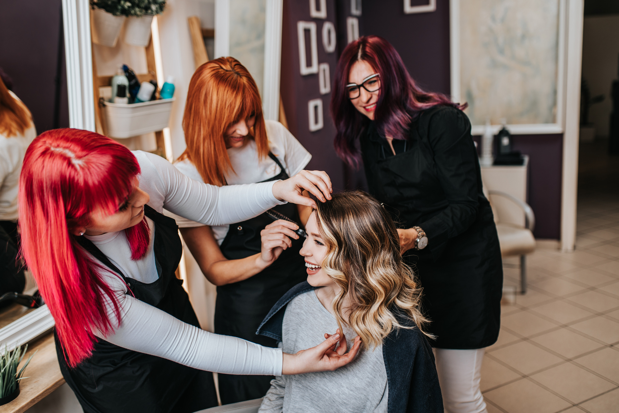 Multiple stylists helping style a woman's hair