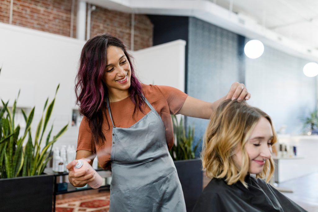 Woman spraying hair spray on styled hair