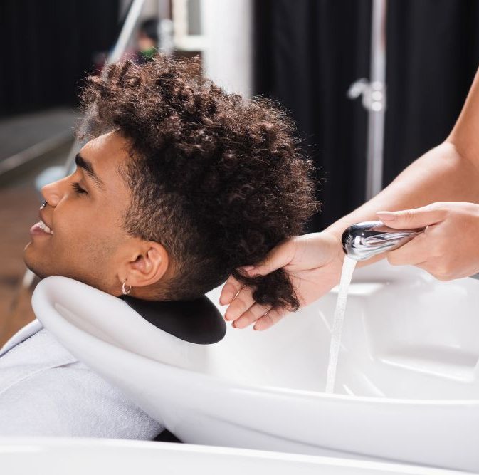 Man having curly hair washed in salon